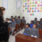 A teacher in a black dress teaching Christian children at MinorCare while the students look attentively at her.