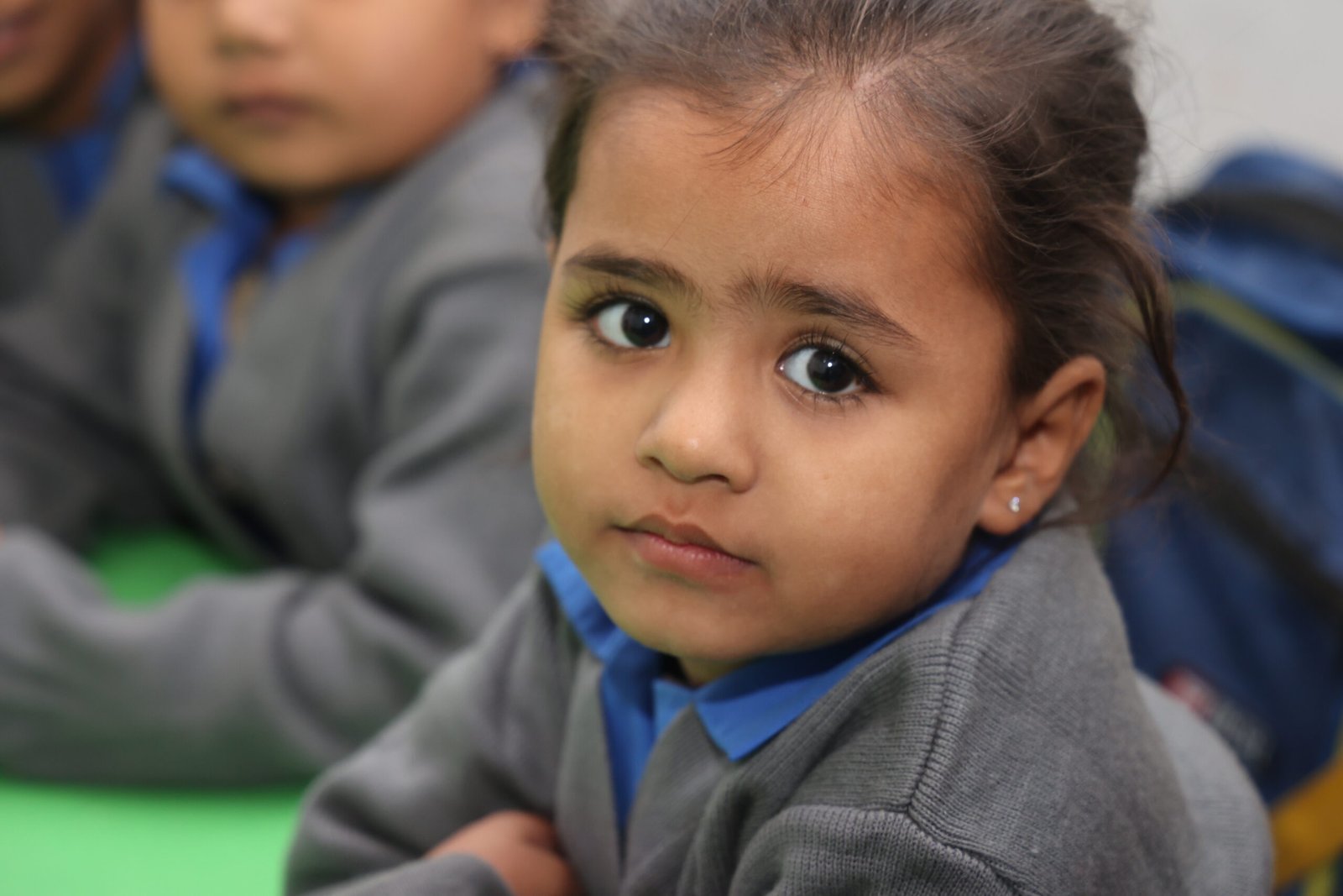 A young Christian girl in a MinorCare school uniform looking at the camera with surprised eyes.