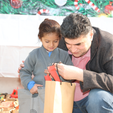 Founder Mo Azeem is sitting with Christian children at MinorCare, leaning in to listen closely to a student.
