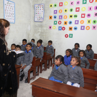 A teacher in a black dress teaching Christian children at MinorCare while the students look attentively at her.