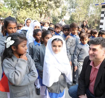 Founder Mo Azeem sitting on his knees with Christian children at MinorCare, engaging warmly with a student.