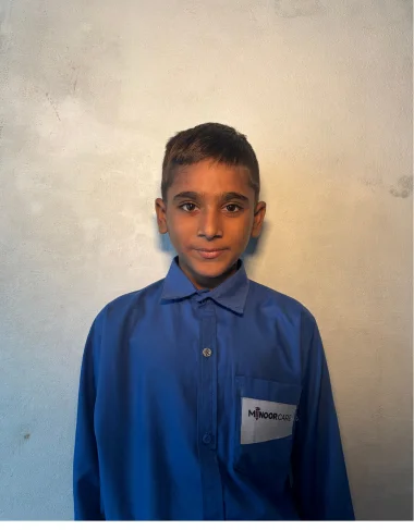 Usman Shafiq, a Christian Grade 5 student supported by MinorCare, smiling in his classroom in Pakistan.