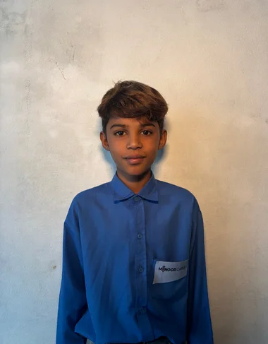 Boiz Azar, a Christian Grade 2 student supported by MinorCare, smiling in his classroom in Pakistan.